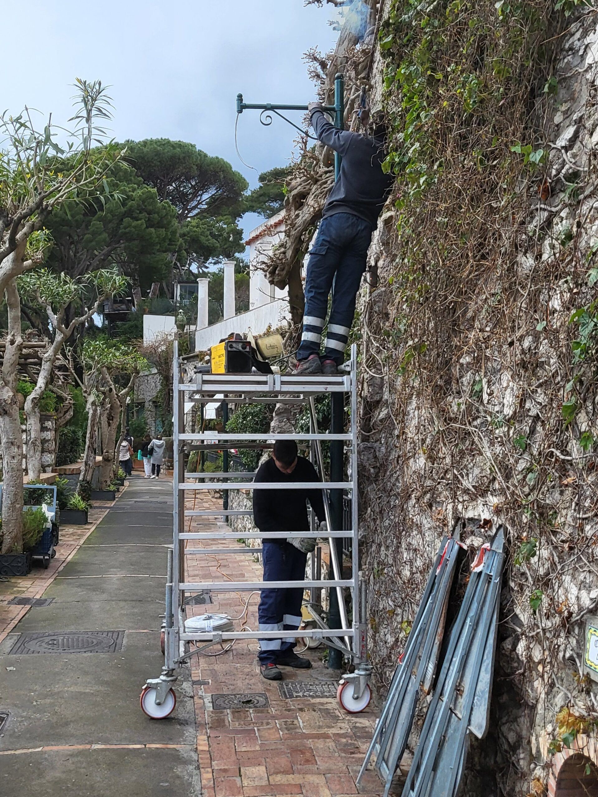 Montaggio di un braccio a parete da trabattello in una via di Capri