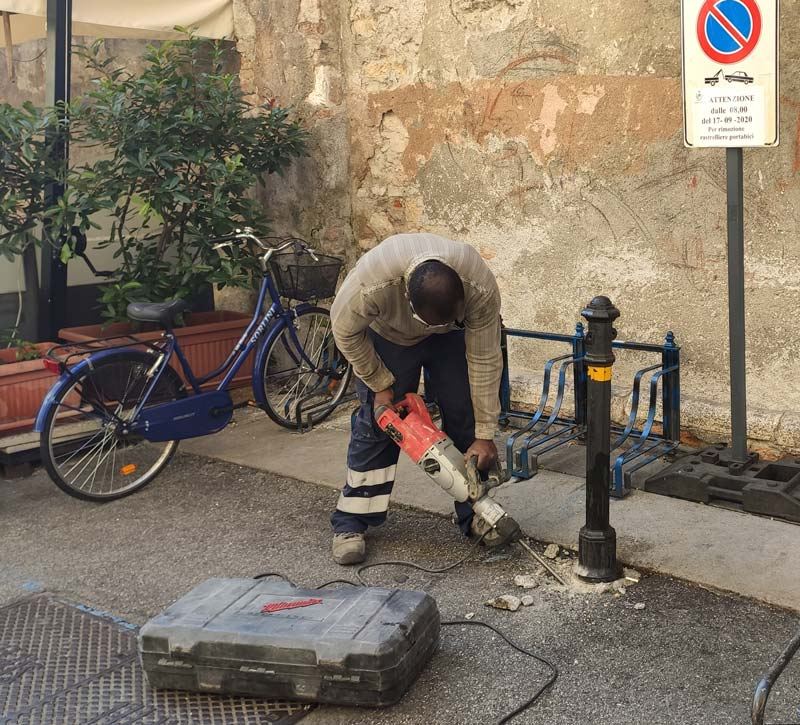 Operaio al lavoro con martello demolitore per la posa di un elemento su pavimentazione
