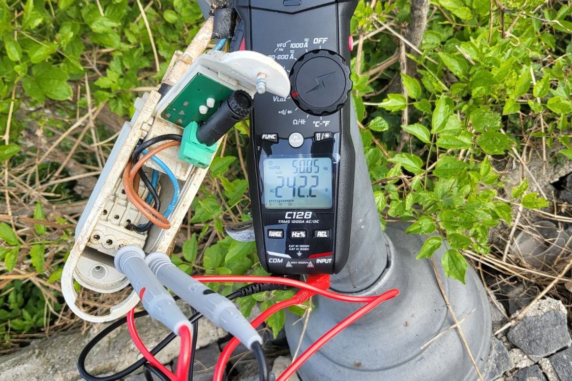 Pinza amperometrica collegata alla morsettiera di un palo durante la verifica strumentale di un impianto elettrico